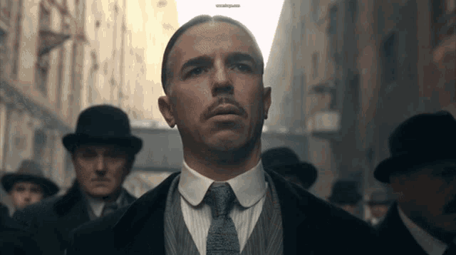 a man in a suit and tie stands in front of a group of men