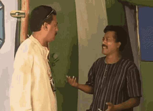 two men are talking to each other in front of a green wall with a sign that says ' a ' on it .