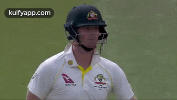 a cricket player wearing a helmet and a white shirt with a qantas logo on it .