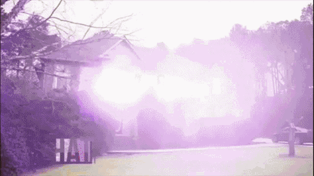 a house is surrounded by trees and purple smoke is coming out of the windows .