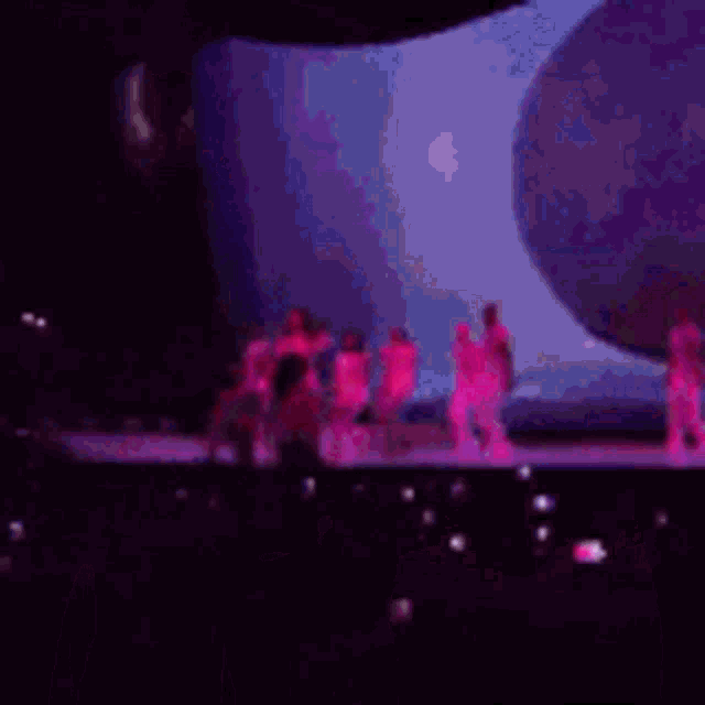 a group of people standing on a stage with purple lights .