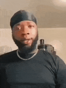 a man with a beard is wearing a black shirt and a headband .