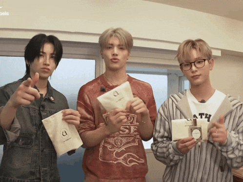 three young men are holding a bottle of perfume and a bag that says a on it