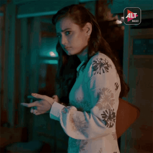 a woman standing in front of a sign that says alt balaji