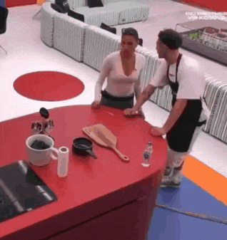 a man and a woman are standing at a red table .