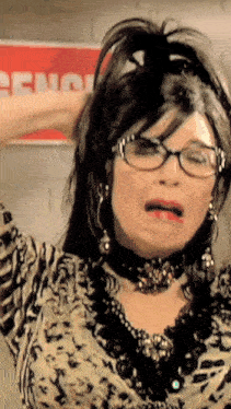 a woman wearing glasses and a choker is making a funny face in front of a sign that says ceno