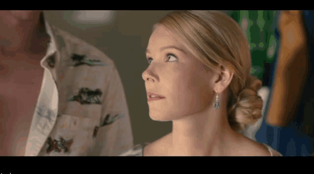 a close up of a woman 's face with a man 's shirt on in the background