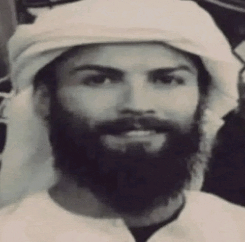 a black and white photo of a man with a beard wearing a white turban