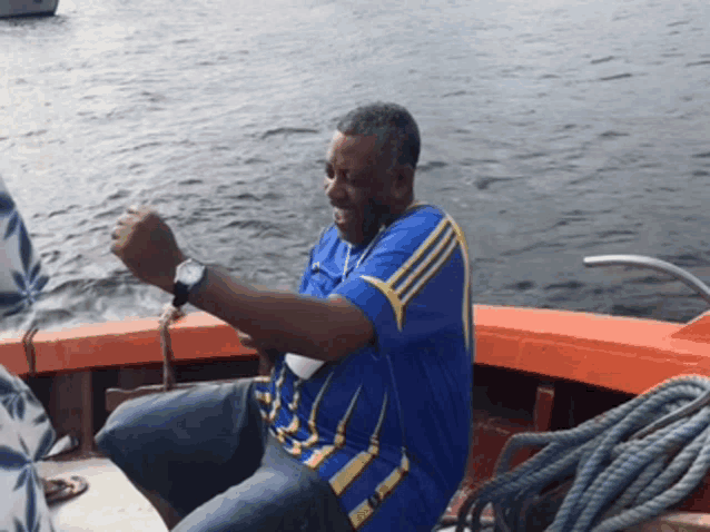 a man in a blue shirt is sitting on a boat