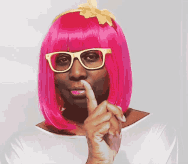 a woman with pink hair and glasses is giving a thumbs up sign