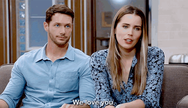 a man and a woman are sitting on a couch and the woman is saying we love you