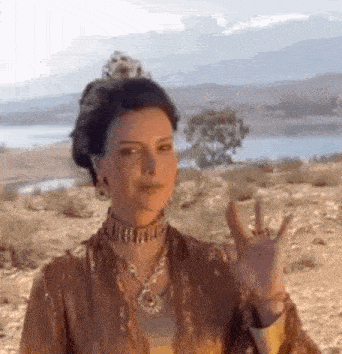 a woman in a crown is giving a thumbs up sign in the desert .