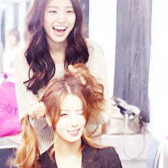 a woman is holding another woman 's hair in front of a pink bag that says ' elin ' on it