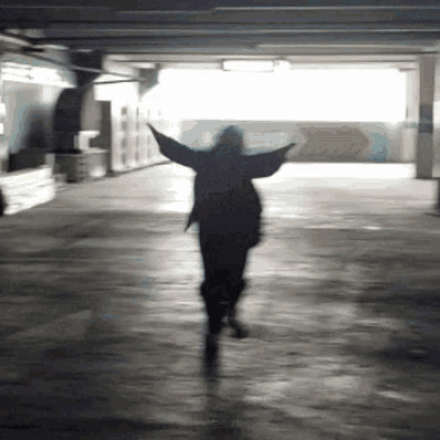a silhouette of a person in a dark room with their arms outstretched