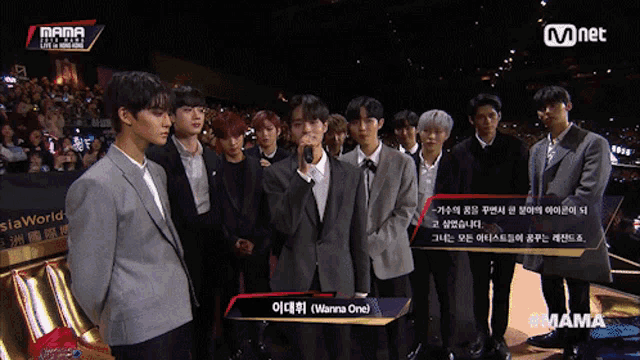 a group of young men are standing in front of a microphone with wanna one standing in front of them