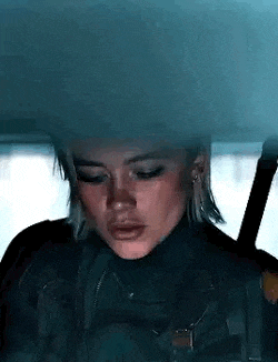 a woman is sitting in a car with her eyes closed and her face covered in smoke .