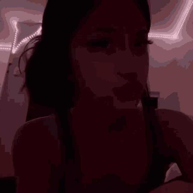 a woman is sitting on a bed in a dark room .