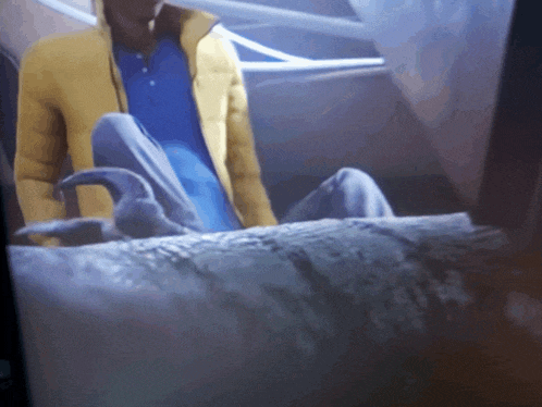 a man in a yellow jacket is sitting on a bed