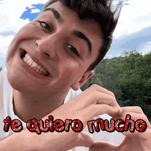 a man is smiling and making a heart with his hands with the words te quiero mucho