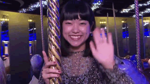 a woman is waving from a merry go round and smiling