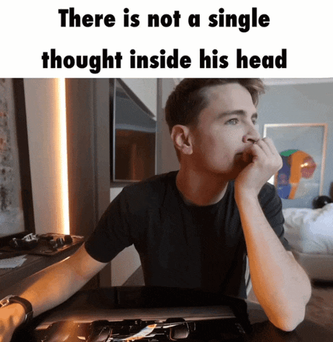 a man is sitting at a desk with his hand on his chin and a meme that says there is not a single thought inside his head
