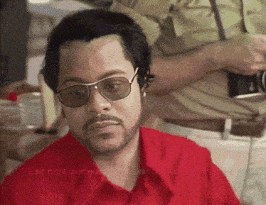 a man wearing sunglasses and a red shirt says " last night someone came and killed me "