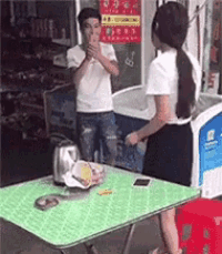a man and a woman are standing around a table .