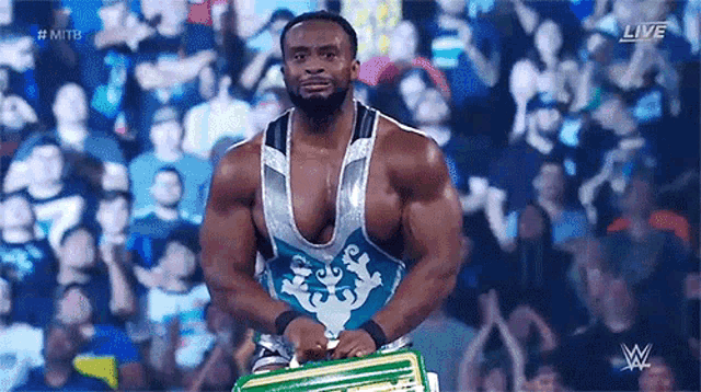 a wrestler is holding a championship belt in front of a crowd of people .