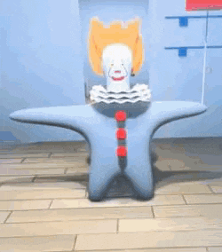 a toy clown is sitting on a wooden floor in a room .