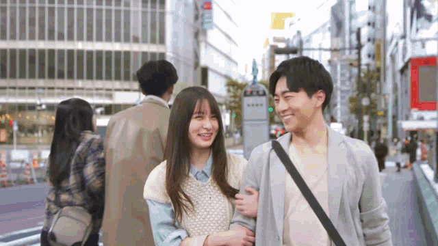 a man and a woman are walking down a street and the woman is smiling
