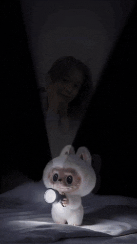 a girl is holding a flashlight next to a stuffed animal with a teddy bear head