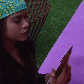 a woman wearing a bandana is sitting at a table looking at her phone .