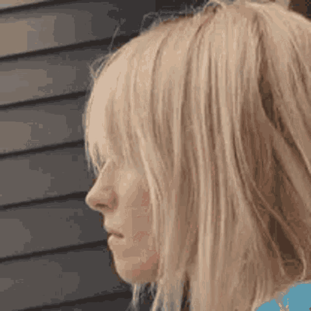 a close up of a woman 's face with long blonde hair and bangs .