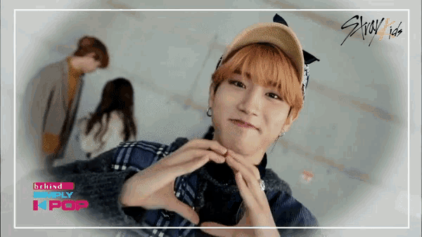 behind simply kpop shows a man making a heart with his hands