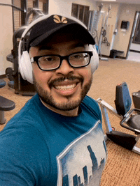 a man wearing a hat and headphones is smiling in a gym