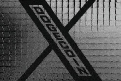 a black and white photo of a brick wall with a x on it .