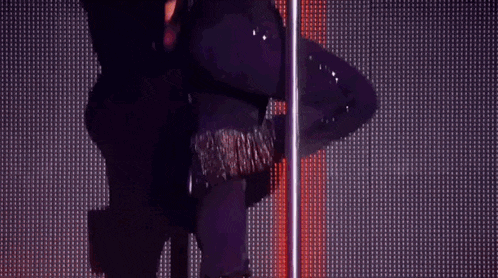 a woman is dancing on a pole in front of a crowd