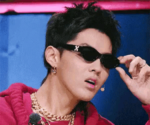 a close up of a person wearing sunglasses and a gold chain .