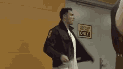 a man is standing in front of a door with his arms outstretched and a sign that says authorized personnel only .