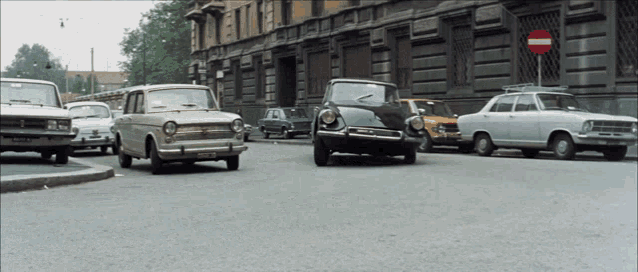 a row of cars are parked on a street with a no entry sign