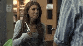 a woman is holding a knife and talking to a man in a room .