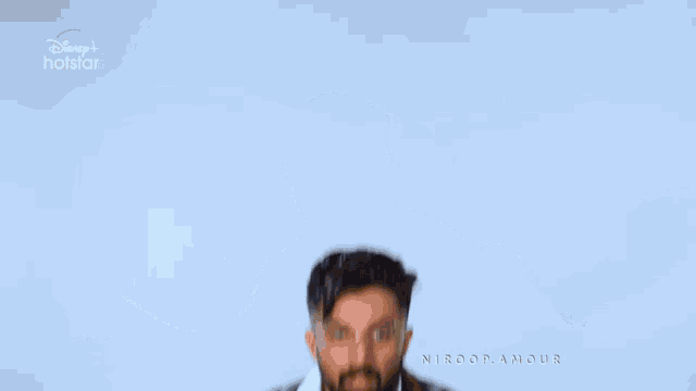 a man wearing glasses and a plaid shirt is dancing in front of a disney+ hotstar logo