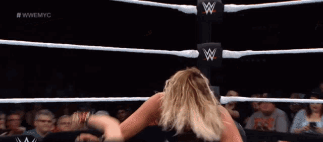 a woman is in a wrestling ring with a w logo on the wall