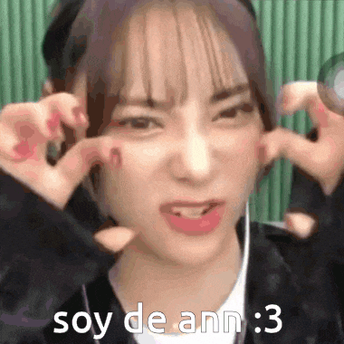 a girl with purple hair is making a funny face and says soy de ann : 3 .