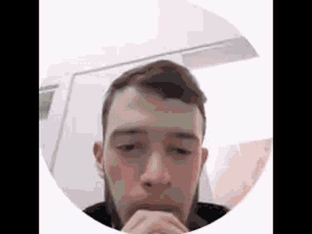 a man with a beard and headphones is sitting in a circle with his hands on his chin .