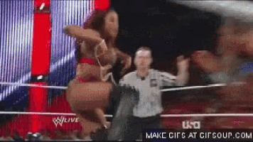 a woman in a bikini is dancing in a wrestling ring while a referee watches