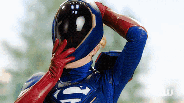 a man in a superman costume covering his face with his helmet