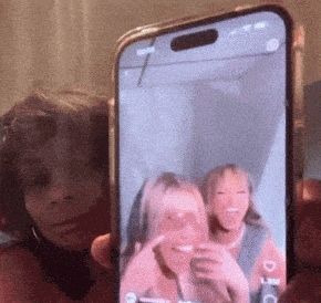 a person is holding a cell phone with a picture of two girls on the screen