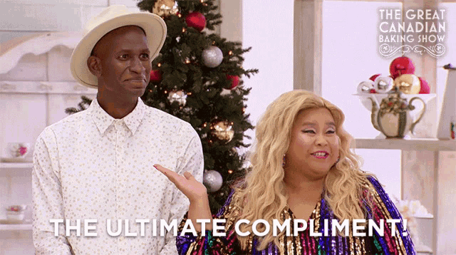 a man and a woman are standing in front of a christmas tree with the words " the ultimate compliment " below them