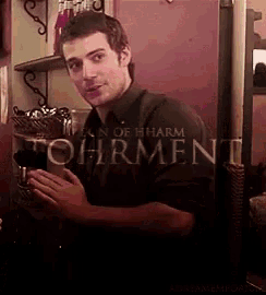 a man in a black shirt is standing in front of a sign that says torment